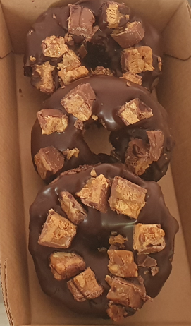 Chocolate brownie with peanut butter chips, topped with chocolate buttercream, drizzled chocolate and snicker chunks